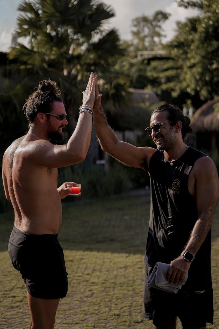 who-we-are Two men engage in a high five celebrating after a workout outdoors.